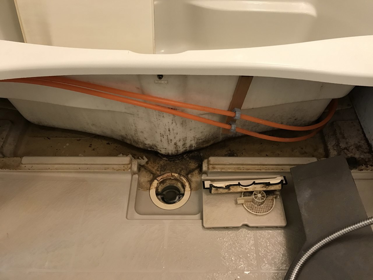 清掃前のエプロン内部。浴槽の下や排水まわりにも汚れがあります。
